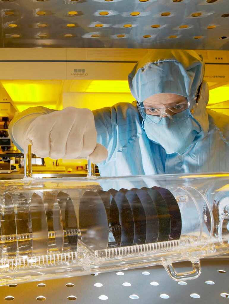 A photo of an INEX staff member observing a collection of semiconductor wafers.