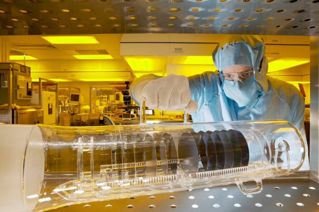 A photo of an INEX staff member observing a collection of semiconductor wafers.